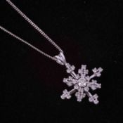 A 9ct white gold 20" curb chain with an 18ct white gold 'snowflake' design pendant set with