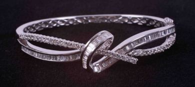 An 18ct white gold knot design bangle set with a mixture of baguette cut, tapered baguette cut &