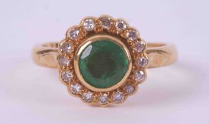 An 18ct yellow gold cluster ring set with a round cut emerald, approx. 0.75 carats in a rub over