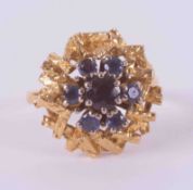 An 18ct yellow gold textured finished cluster style ring set with seven round cut sapphires, total