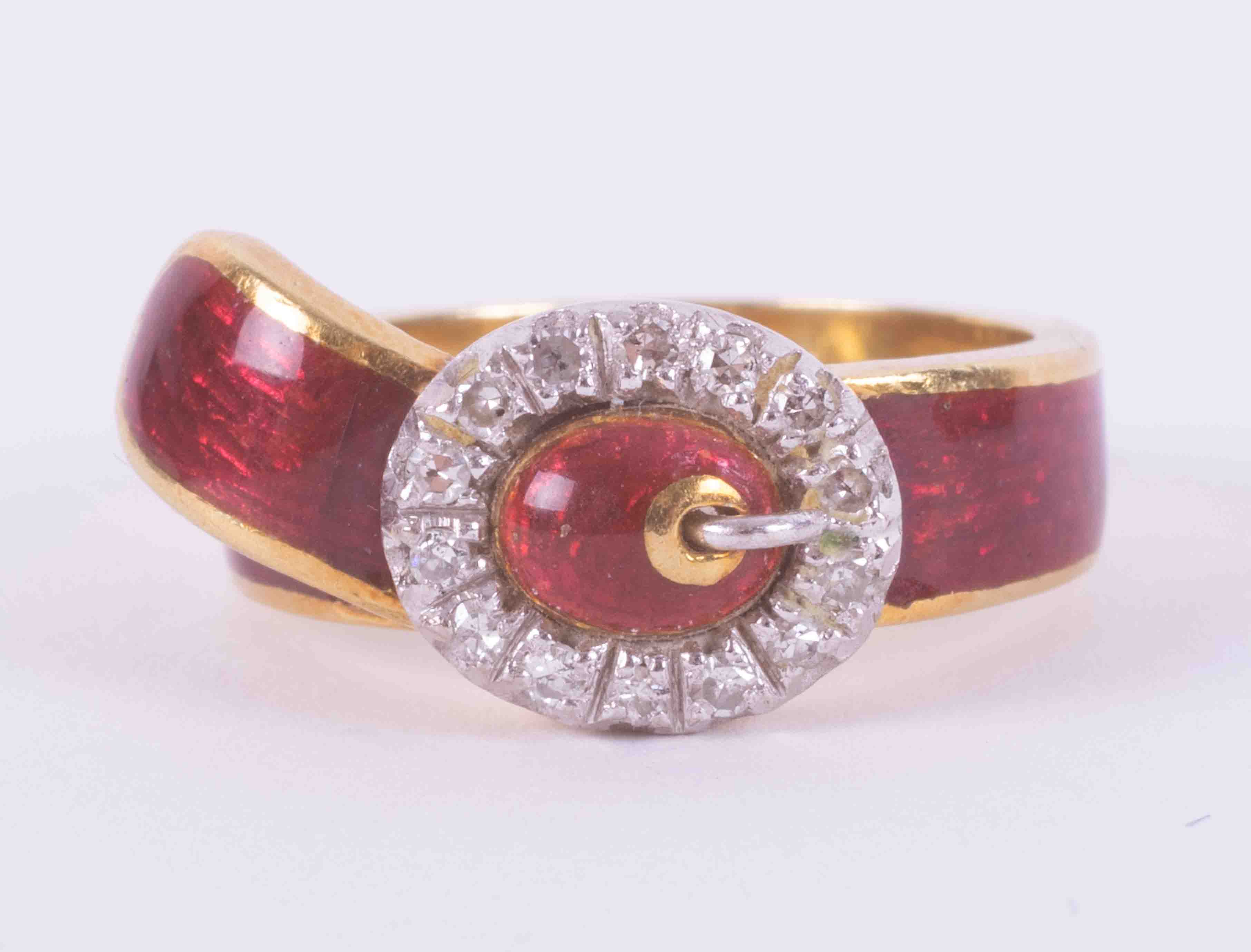 An 18ct yellow gold buckle design ring with red enamel and 14 round old round cut diamonds, total