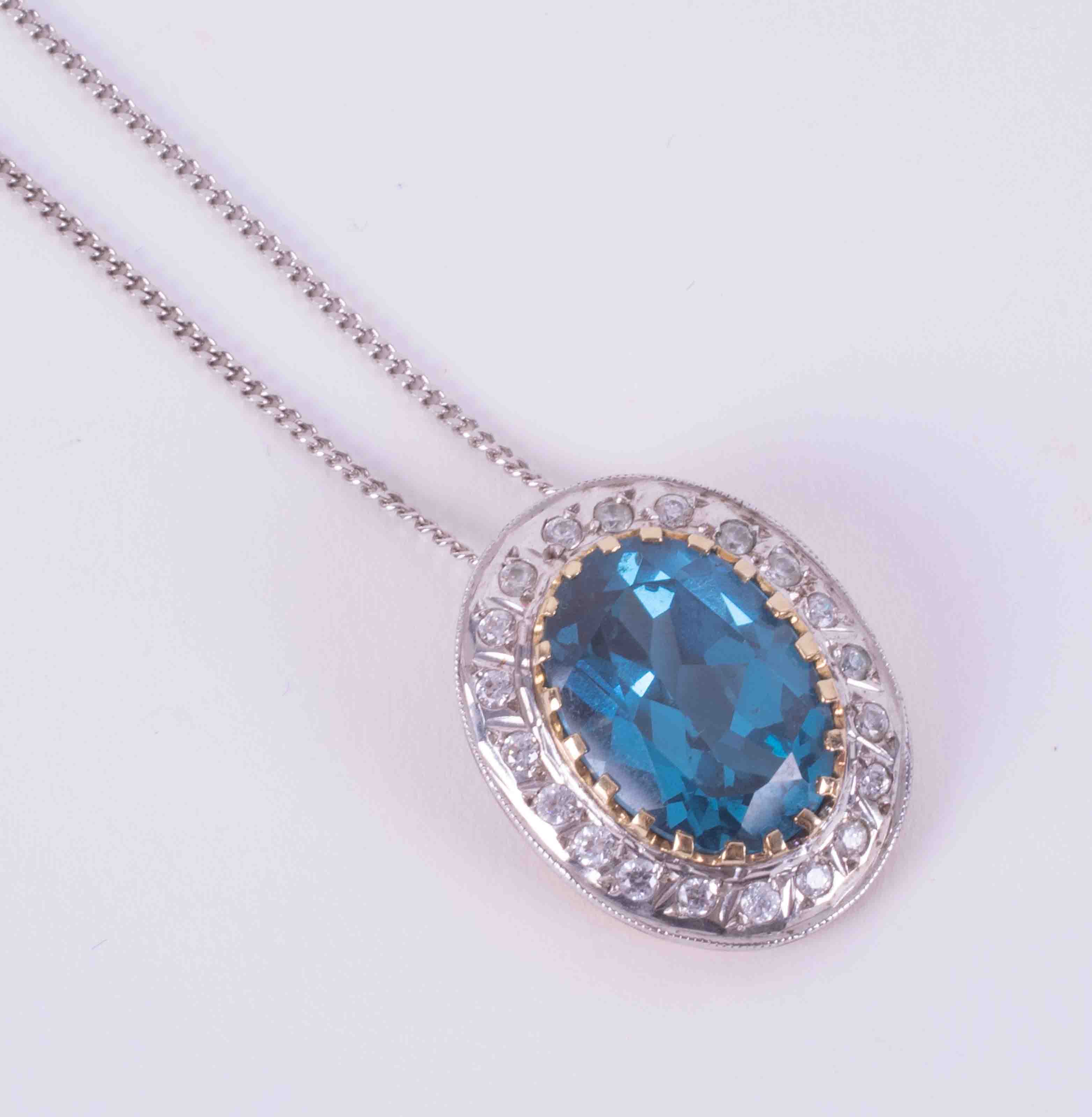 A 9ct white gold 18" curb chain with a 14ct yellow & white gold pendant set with paste blue &