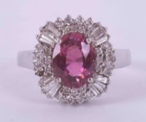 An 18ct white gold cluster ring set with a central oval cut pink tourmaline?, surrounded by