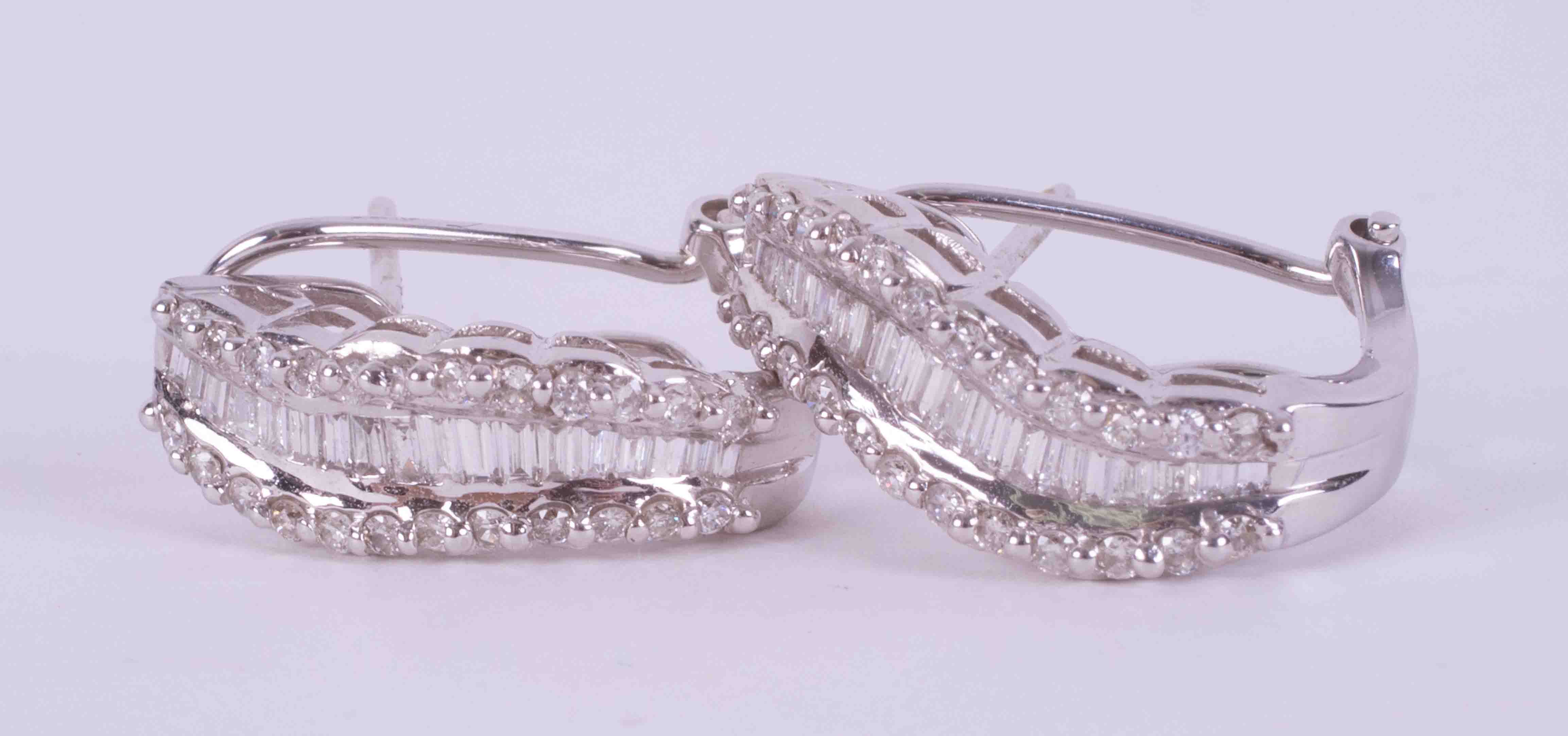 A pair of 18ct white gold wave design earrings set with approx. 1.34 carats total weight of baguette