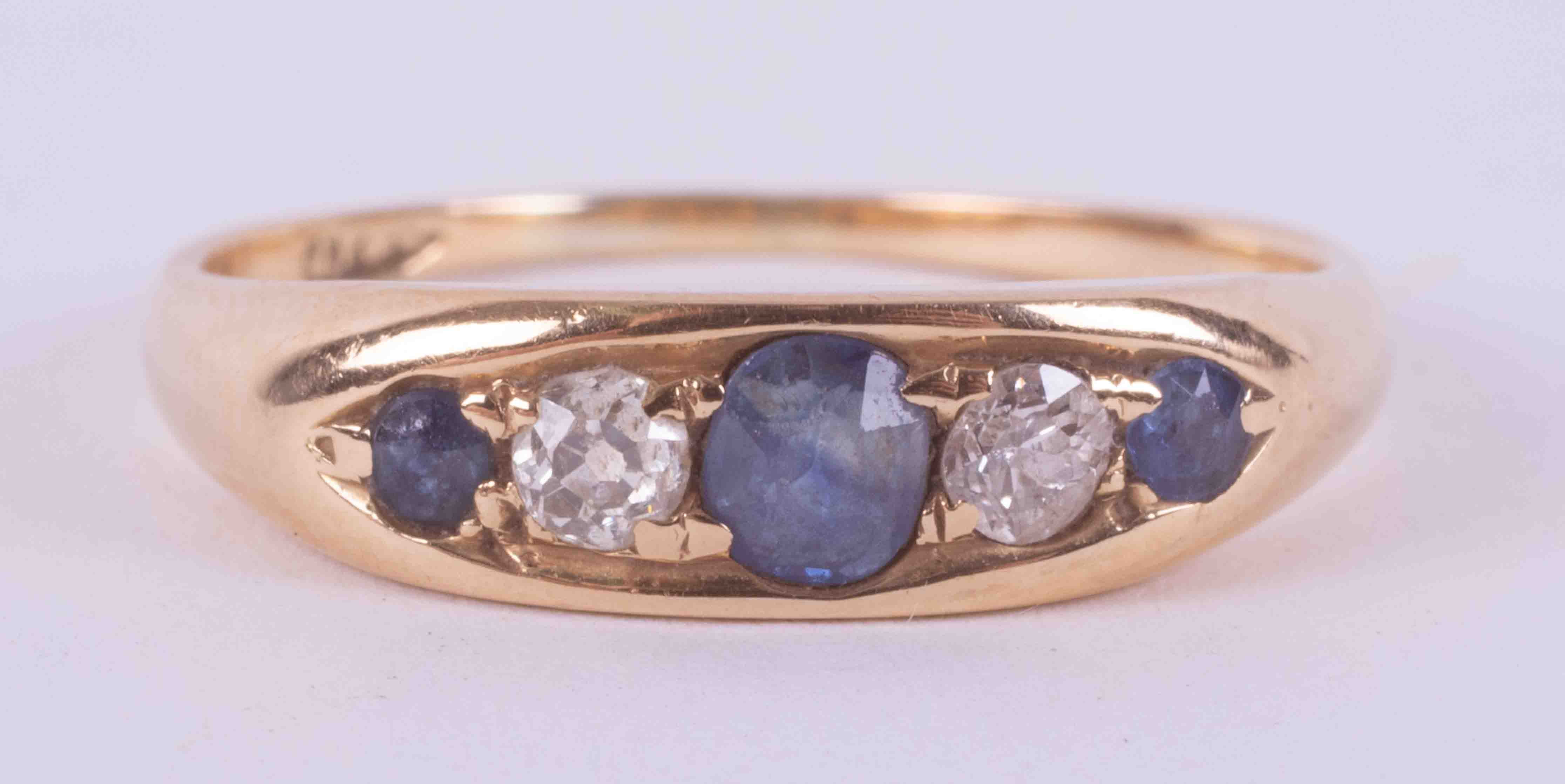 An 18ct yellow gold ring, set with two round cut sapphires & a central set oval cut