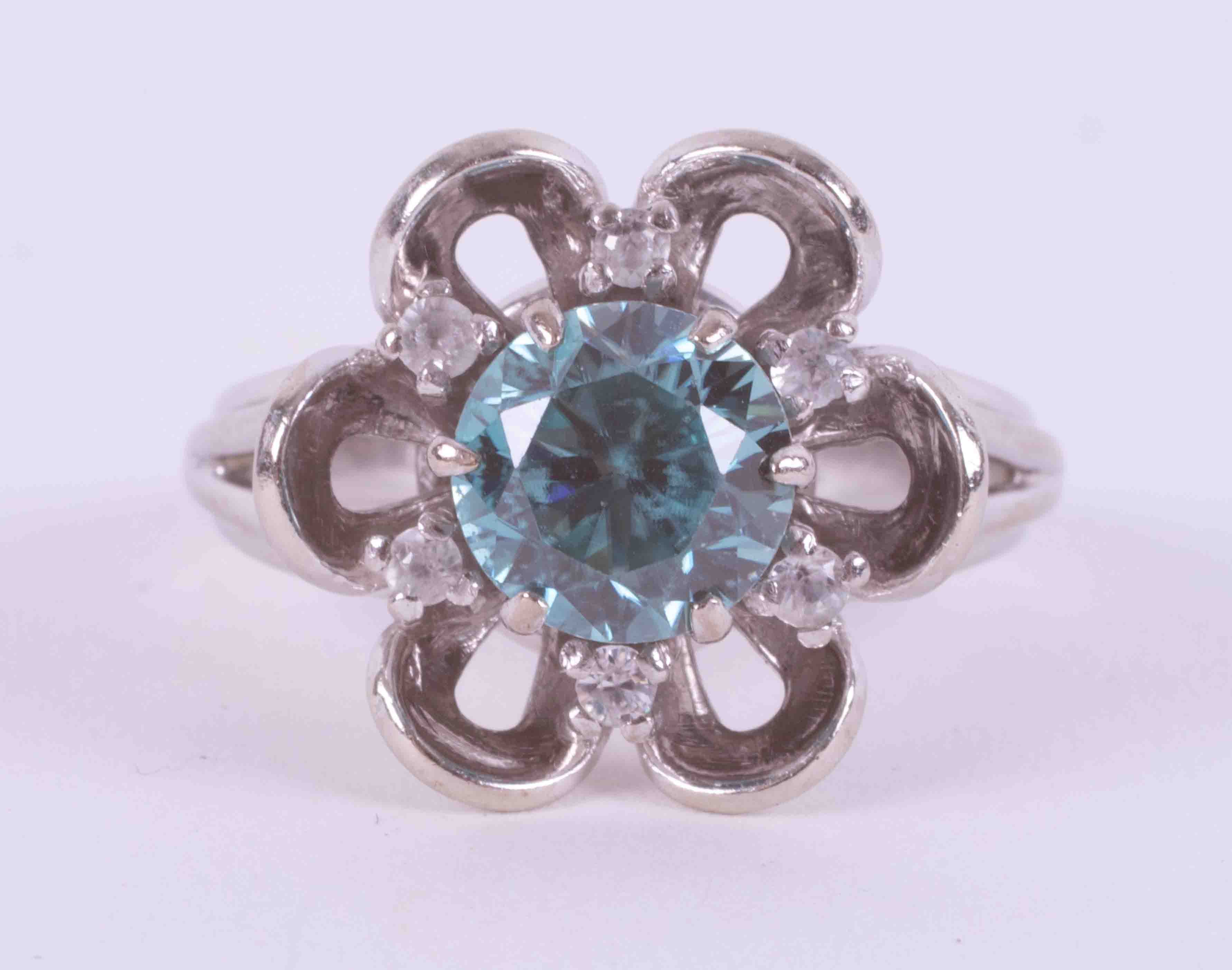 A 14ct white gold flower ring set with a central round cut blue zircon, approx. 1.47 carats,