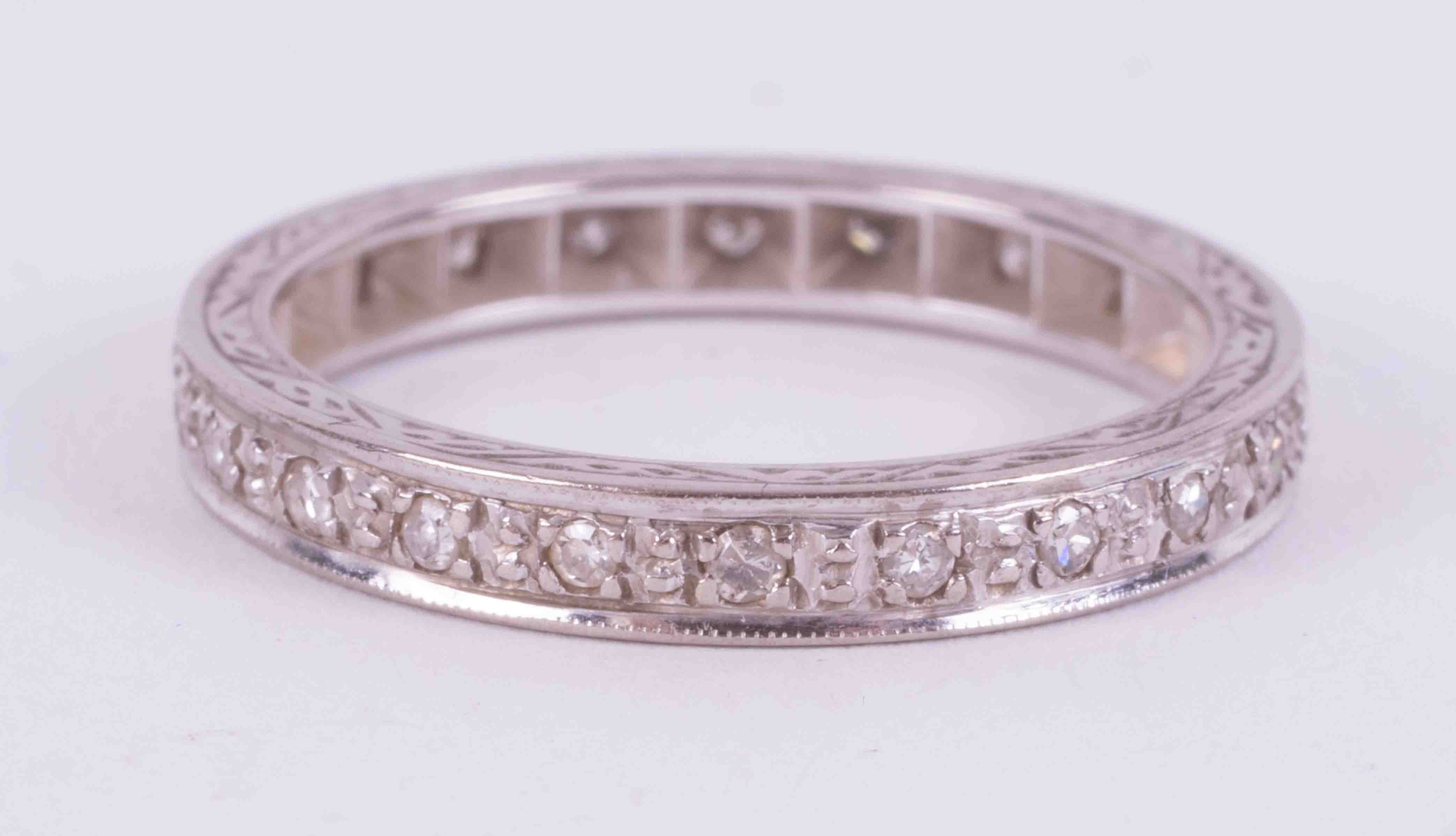 An 18ct white gold full eternity ring set with small old cut diamonds and engraving on the edges,