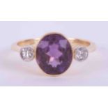 An 18ct yellow gold & platinum antique three stone ring set with a central oval cut amethyst,