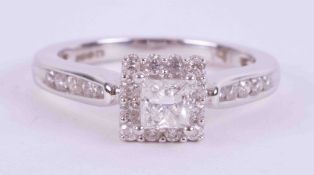 An 18ct white gold ring set with a central princess cut diamond surrounded by small round