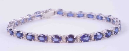 An 18ct white gold line bracelet set with twenty six oval cut sapphires, total weight approx. 9.00