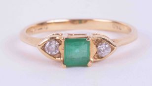 An 18ct yellow gold three stone ring set with a central square cut emerald, approx. 0.31 carats,