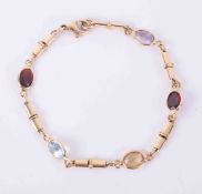 An 18ct yellow gold bracelet set with oval cut multi-coloured gemstones including blue topaz,