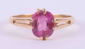 An 18ct yellow gold (not hallmarked or tested) ring set with an oval cut pink sapphire,