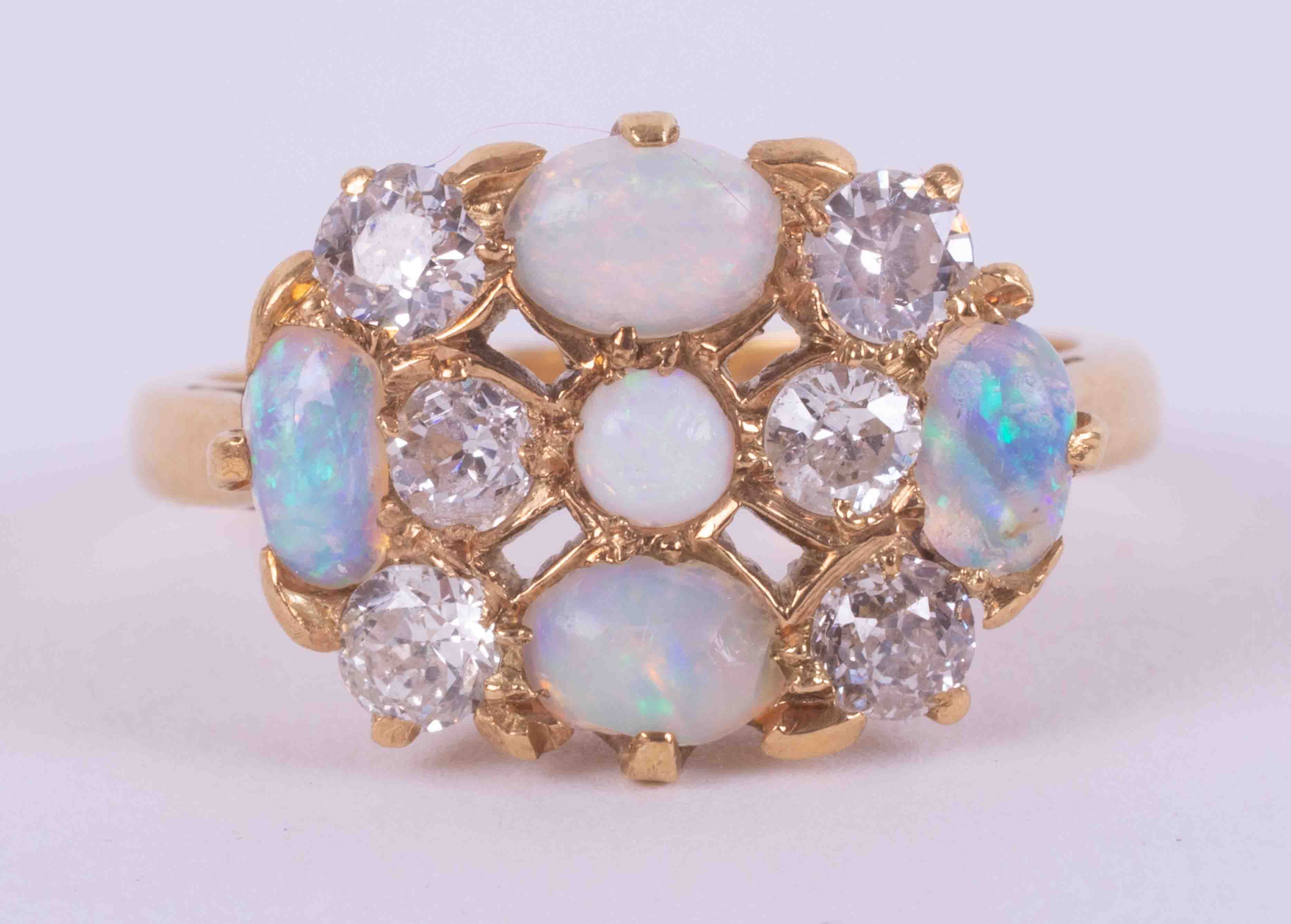 An 18ct yellow gold cluster style ring set with four oval cabochon cut white opals and a