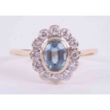 An 18ct yellow & white gold cluster ring set with a central oval cut aquamarine approx. 0.65 carats,
