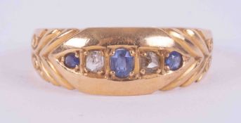 An 18ct yellow gold gypsy style ring set with three small sapphires, two round & one oval cut, and