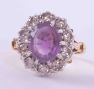 An 18ct yellow & white gold cluster ring set with an oval cut amethyst, approx. 2.18 carats,