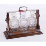 A three bottle oak cased tantalus with inscribed plaque dated 1930, height 31cm, with key (one