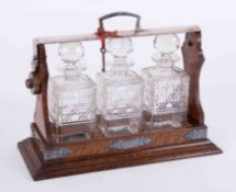 A three bottle oak cased tantalus with inscribed plaque dated 1930, height 31cm, with key (one