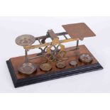 A set of Post Office scales in brass with graduated five weights on wood base, marked Mordan & Co,