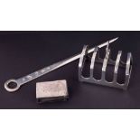 A silver meat skewer 58gms, George V silver five bar toast rack 58gms and a silver matchbox case (