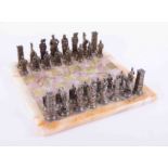 A complete set of thirty two silver and gold coloured chess pieces with a green onyx board.
