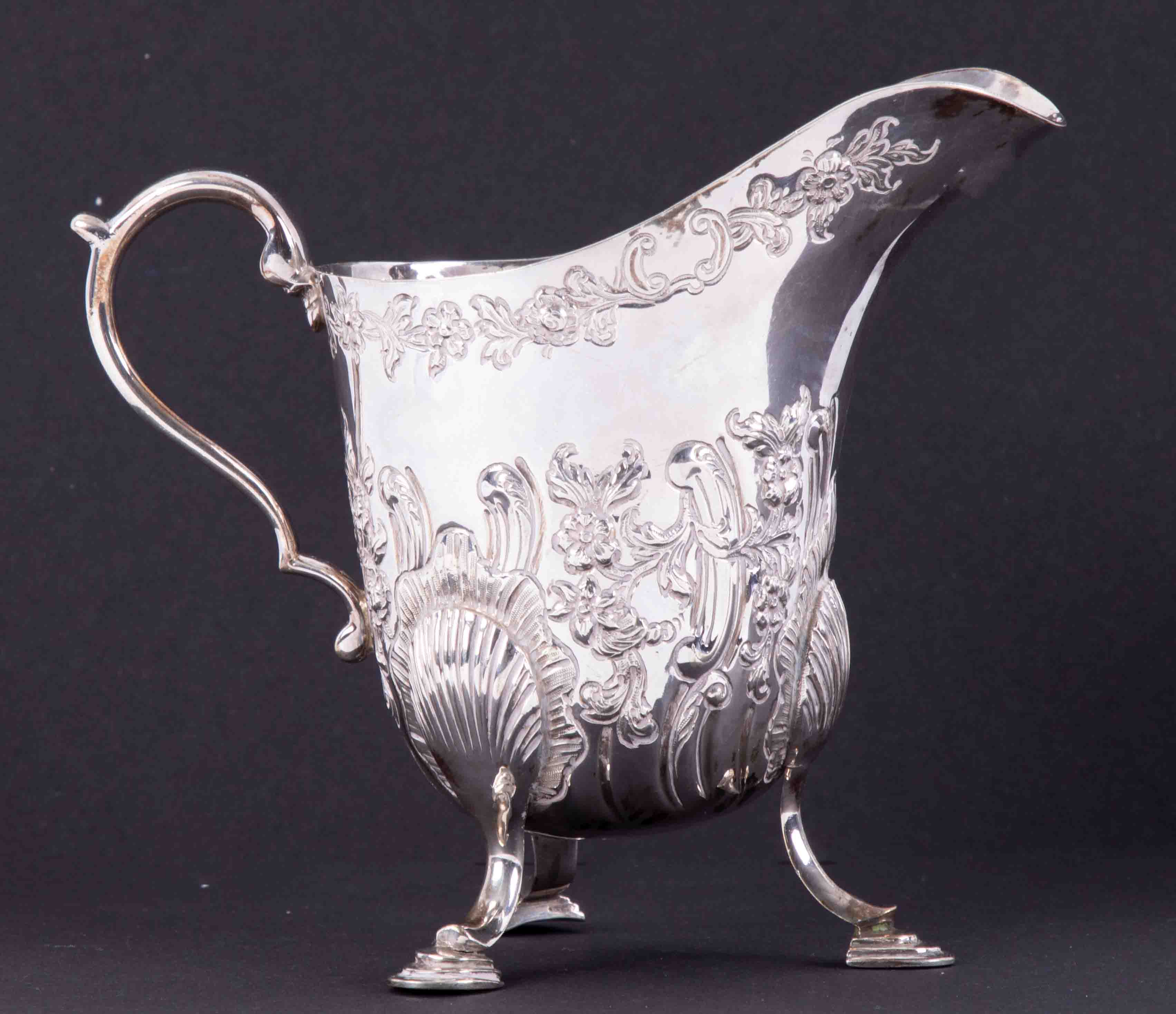 An Irish silver embossed cream jug HM West & Son, Dublin, 234gms, height 12cm.