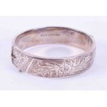 A solid silver bangle, engraved, with safety chain, approx 25.60gms.