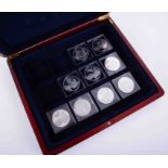 Nine silver crowns, Monarchs of England, each 28.7gm in a mahogany effect case.