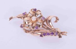 A 9ct yellow gold flower brooch set with amethysts and a pearl, 7.74gm, length approx. 5cm with
