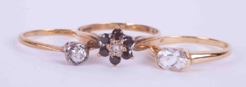 Three rings, one a 9ct yellow gold ring in a flower design set with small round cut dark blue