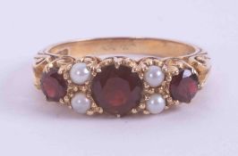 A 9ct yellow gold gypsy style scroll ring set with three round cut garnets and four seed pearls, 3.