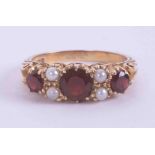 A 9ct yellow gold gypsy style scroll ring set with three round cut garnets and four seed pearls, 3.