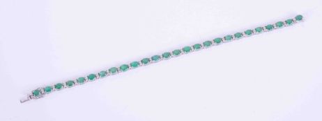 An 18ct white gold bracelet set with 10 carats of oval cut emeralds, interspaced with 0.55 carats