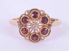 An 18ct yellow gold cluster style ring set with six round cut garnets and six old round cut diamonds