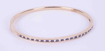 A 9ct yellow gold bangle set with a mixture of round brilliant cut diamonds & sapphires, with hinge,