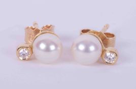 A pair of 18ct yellow gold studs set with a 5.5mm cultured pearl and a small round brilliant cut