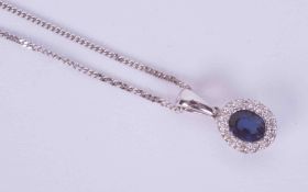 An 18ct white gold cluster style pendant set with a central oval sapphire, approx. 0.26 carats,