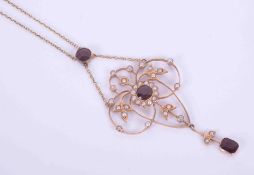 A yellow gold Art Nouveau ornate flower design necklace set with garnets and seed pearls, with a