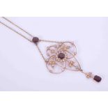 A yellow gold Art Nouveau ornate flower design necklace set with garnets and seed pearls, with a