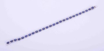 An 18ct white gold bracelet set with 10 carats of oval cut sapphires interspaced with 0.55 carats of