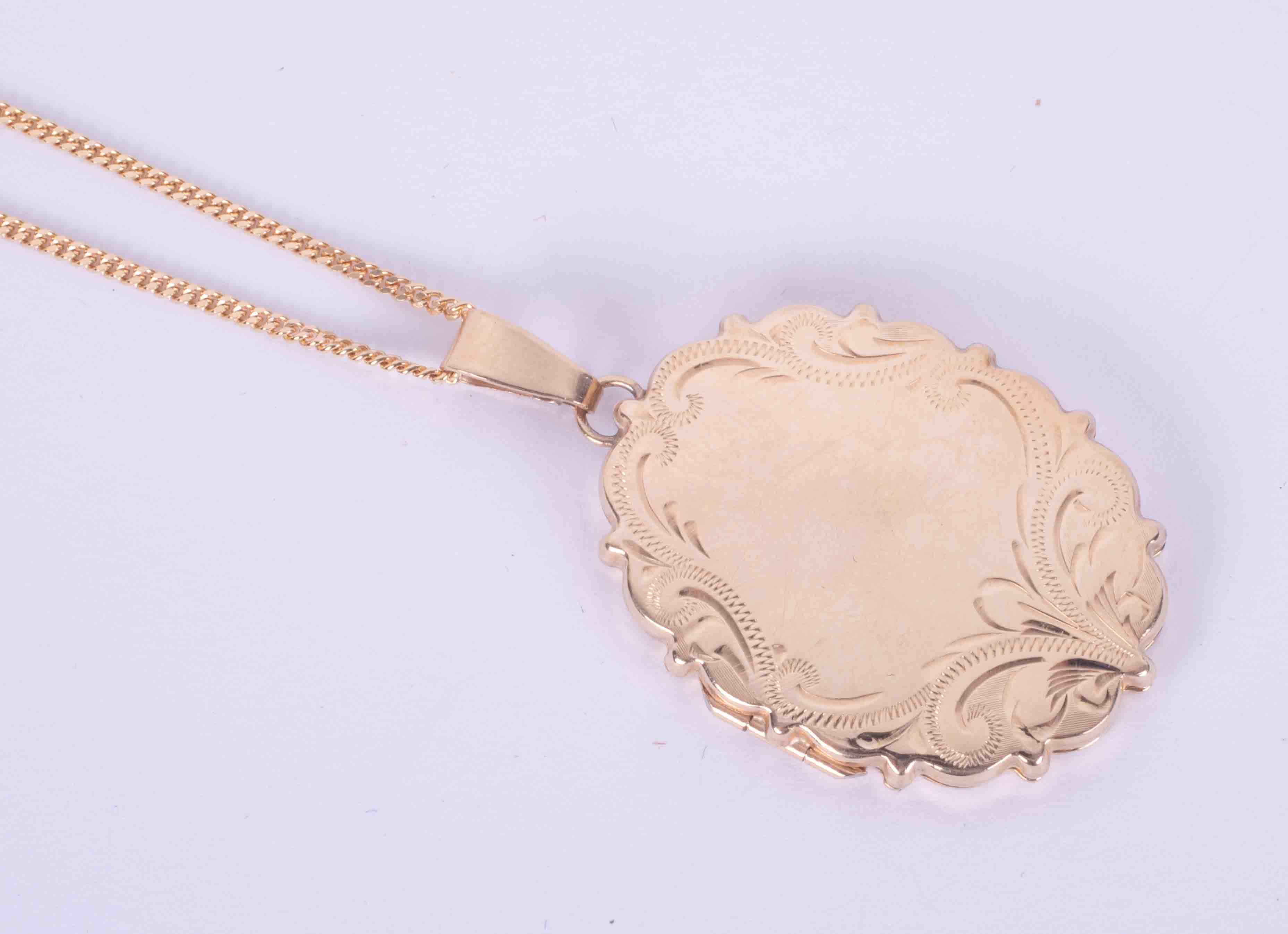 A 9ct yellow gold oval engraved scalloped edged locket, measuring approx. 3.5cm x 2.5cm (not