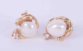 A pair of 9ct yellow gold stud earrings set with a white baroque pearl, surmounted by a gold swirl