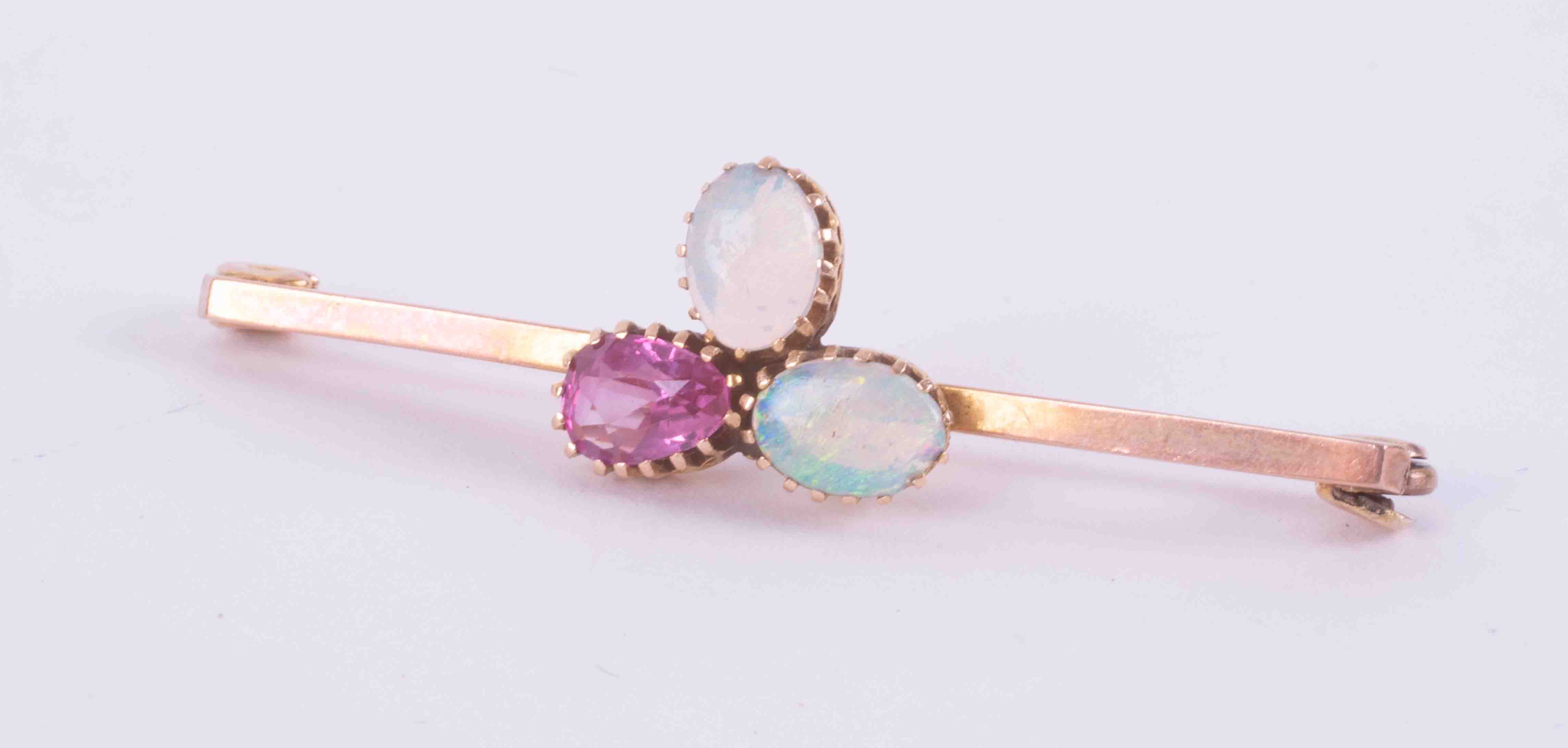 A 9ct rose gold bar brooch set with two white cabochon cut oval opals, measuring approx. 6.5mm x 4.
