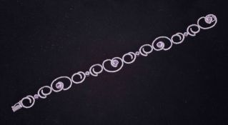 An 18ct white gold swirl design bracelet set with small round cut diamonds and eight round cut