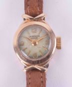 J.W.Benson, a ladies 9ct yellow gold small round face wristwatch, with tan strap, boxed.