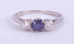 A platinum (no hallmarks & not tested) three stone ring set with a central round cut sapphire,