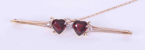 A yellow gold (not hallmarked or tested) bar brooch with two heart shaped garnets measuring