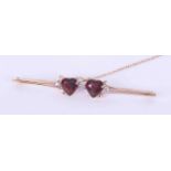 A yellow gold (not hallmarked or tested) bar brooch with two heart shaped garnets measuring