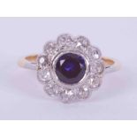 An 18ct yellow gold & platinum flower cluster style ring set central with a round cut sapphire,